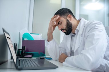 Male doctor in a white robe feeling tired