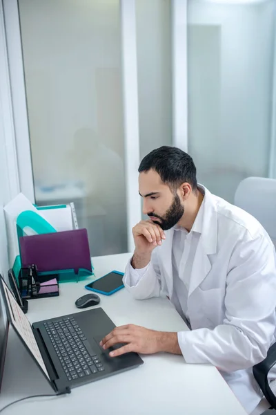 Medico maschio in vestaglia bianca che lavora al computer portatile — Foto Stock