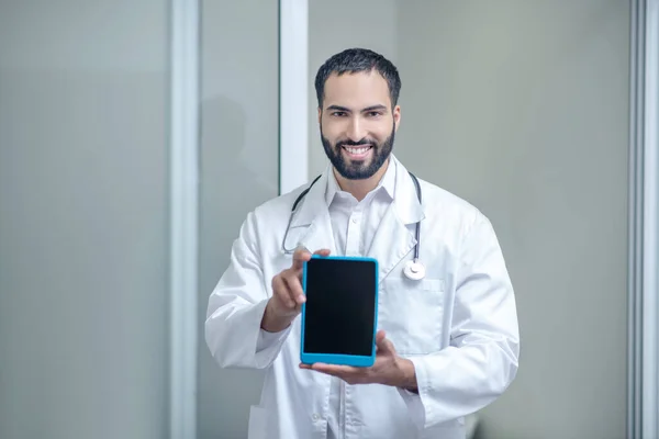 Мужчина-врач в белом халате держит планшет в руках — стоковое фото