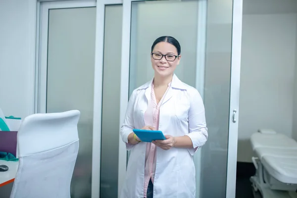 Médico de cabelos escuros feminino em óculos sorrindo muito bem — Fotografia de Stock