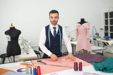 Male tailor standing, outlining pattern on cloth
