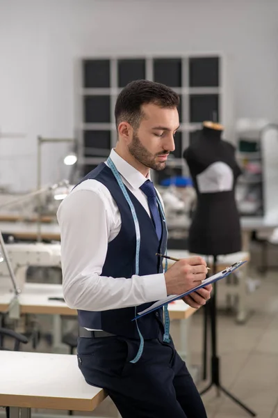 Adaptador masculino sosteniendo la carpeta del clip, tomando notas — Foto de Stock