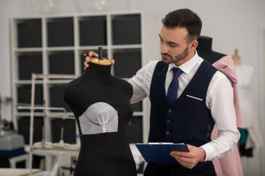 Male tailor touching dummy, creating new model