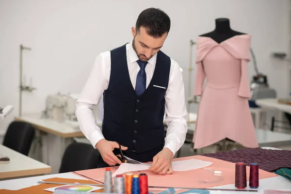 Sastre masculino de pie y recortar el patrón de papel — Foto de Stock