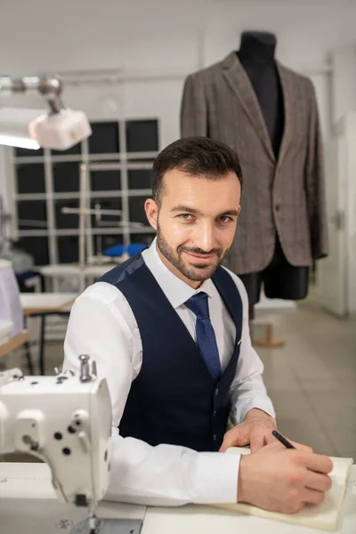 Diseñador de moda masculino sentado, tomando notas, sonriendo — Foto de Stock