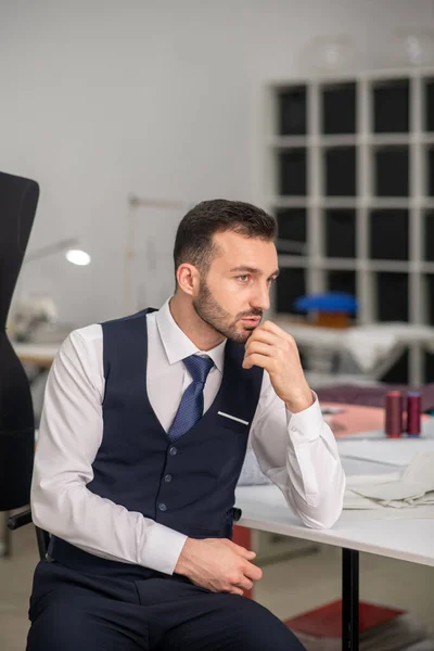 Male tailor sitting, propping his chin on hand — ストック写真