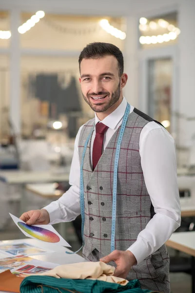 Male tailor holding color palette, choosing cloth, smiling — ストック写真