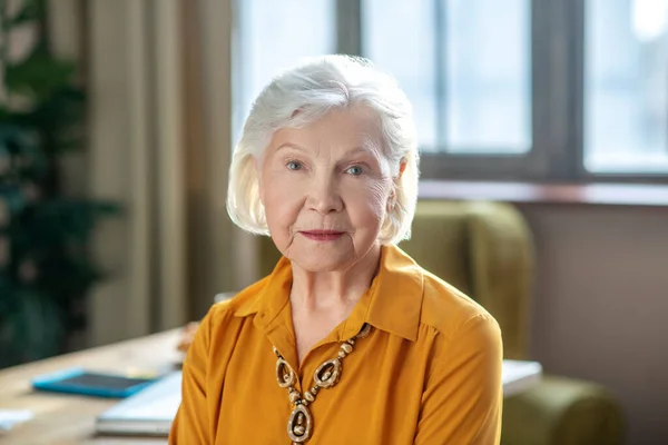 Grijsharige elegante vrouw met kralen om haar nek — Stockfoto