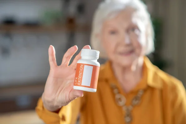 Mujer guapa de pelo gris sosteniendo un frasco con vitaminas en las manos — Foto de Stock