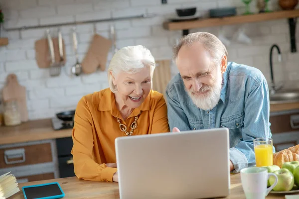 Glada äldre par som har ett videosamtal och ler — Stockfoto