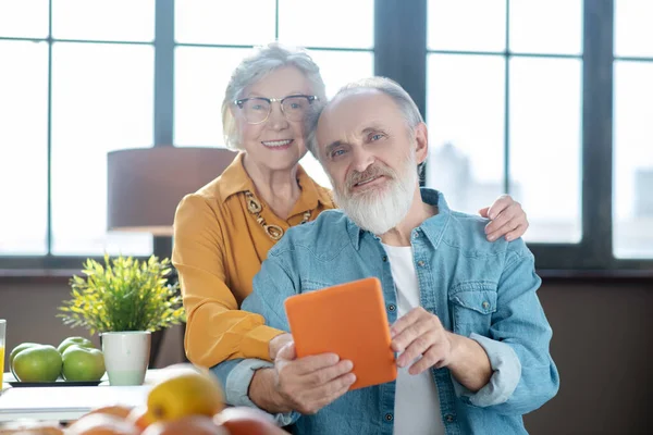 Älterer Mann zeigt seiner Frau, wie man ein Tablet bedient — Stockfoto