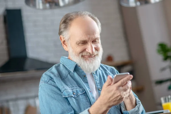 Gülümseyen yaşlı adam yeni akıllı telefonunu kullanıyor. — Stok fotoğraf