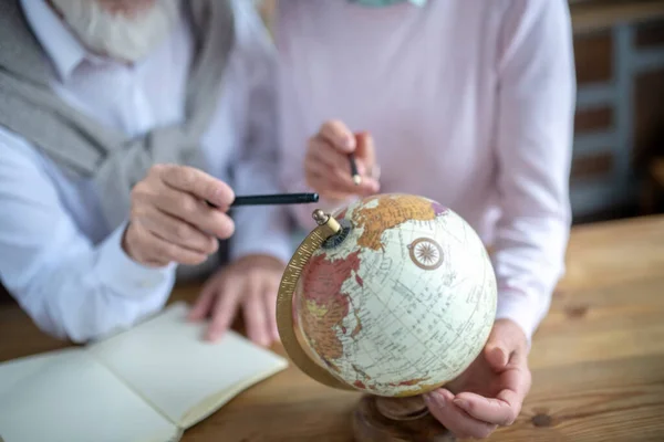 Couple of pensioners spinning the old globe — Stock Photo, Image