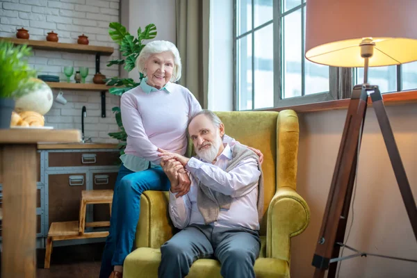 Прекрасная пожилая пара, сидящая в желтом кресле — стоковое фото