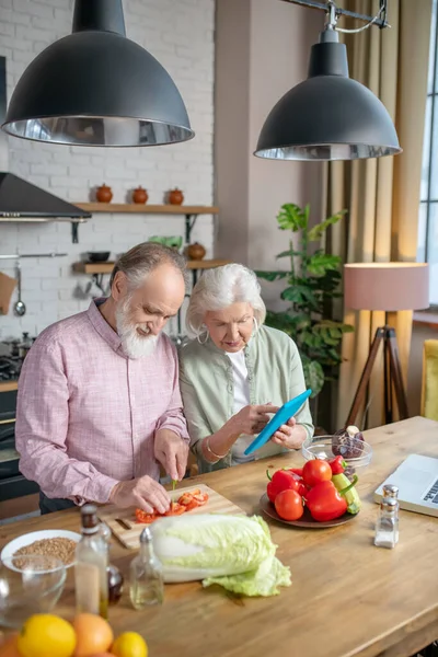 Ældre par bruger opskrifter fra internettet, mens madlavning - Stock-foto