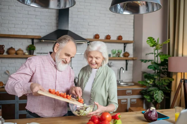 Anciano y mujer cortando tomates para una ensalada juntos — Foto de Stock