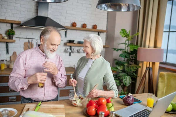 Personas mayores charlando animadamente mientras cocinan juntas — Foto de Stock