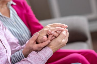 Man and woman sitting on the sofa holding each others hands