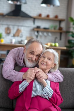 Bearded grey-haired man hugging his wife with tenderness