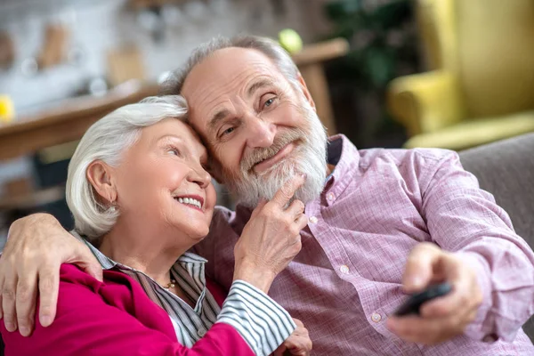 Grey-haired smiling woman touching her husbands beard and looking thoughtful — Φωτογραφία Αρχείου