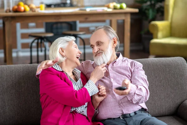 Grey-haired smiling woman touching her husbands beard — Zdjęcie stockowe