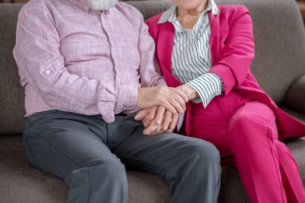 Чоловік і дружина сидять на дивані, тримаючи один одного за руки — стокове фото