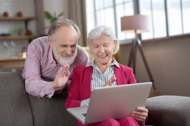 Elderly married couple feeling happy while having video call