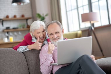 Elderly married couple looking joyful while having video call