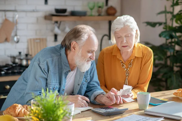 Elderly married couple making calculations together and looking involved — Stock fotografie