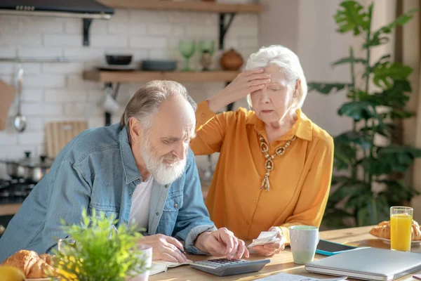 Elderly married couple making calculations together and looking disturbed — Stockfoto