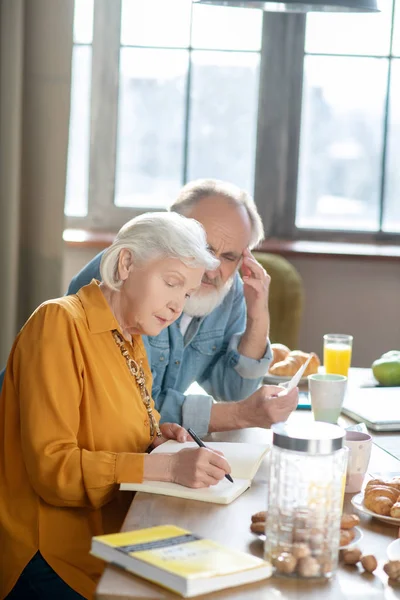 Pareja de ancianos casados sentados en la mesa haciendo cálculos juntos — Foto de Stock