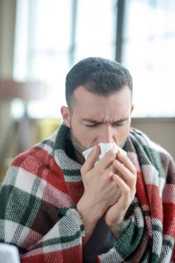 Dark-haired young sick man sneezing and feeling unwell