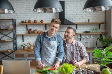 Young gay couple making breakfast together and smiling