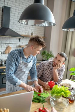 Young gay couple cooking breakfast together feeling happy