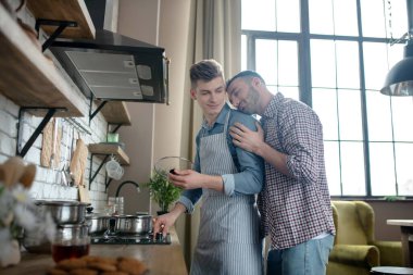 Male couple standing by the hob of the house.
