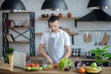 Young man standing at the table in the kitchen.