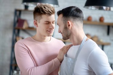 Two young men standing close together looking into the eyes.
