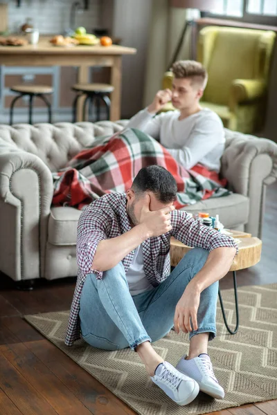 Young man in a checkered shirt feeling desperate — Stockfoto