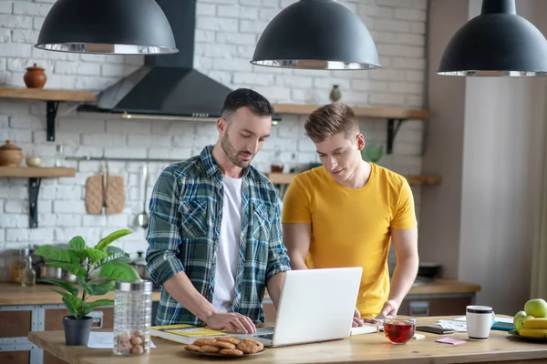 Dos jóvenes de pie cerca de la mesa y viendo el vídeo — Foto de Stock