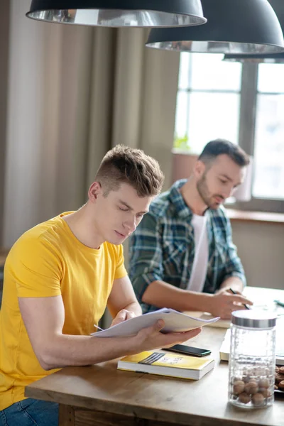 Deux jeunes hommes travaillant ensemble sur le projet et regardant concentré — Photo