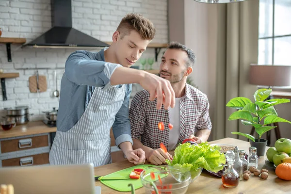 Young men cooking vegetable salad in the kitchen.. — Stockfoto