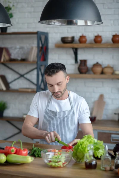 Hombre atento picando pimienta en una tabla de cortar . — Foto de Stock