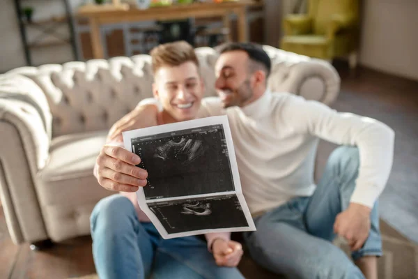 Ultrasound result in the hand of a young happy man. — Stockfoto