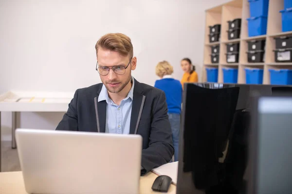 Profesor masculino sentado en el escritorio, frente a la computadora portátil — Foto de Stock