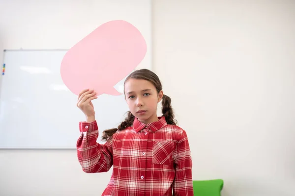 Girl holding pink dialogue cloud, looking upset — Stock Photo, Image