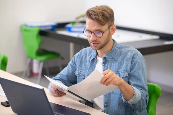 노트북에 앉아서 서류를 확인하는 남자 교사 — 스톡 사진