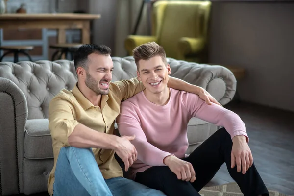Gay casal sentado no o chão e sorrindo — Fotografia de Stock