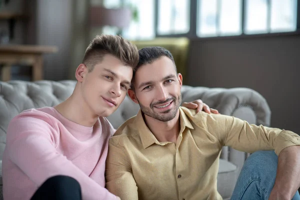 Gay paar zitten op de vloer op zoek vreedzame — Stockfoto