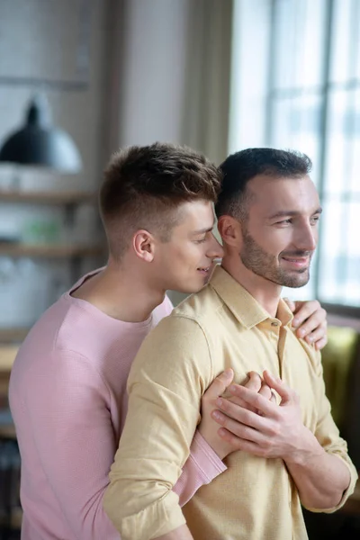 Unga homosexuella par som står i rummet och kramas — Stockfoto