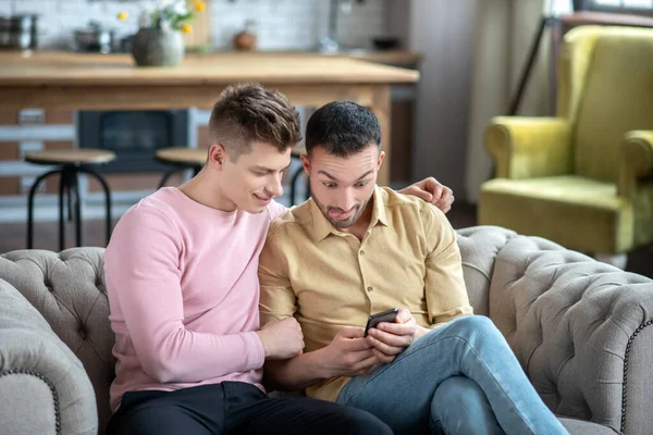 Barbudo hombre buscando sorprendido mientras viendo vídeo junto con su pareja — Foto de Stock